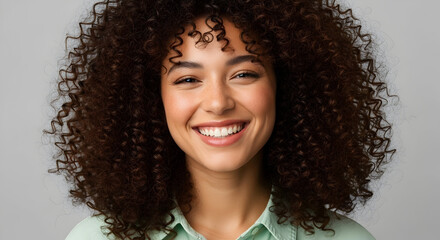 Happy young woman with curly hair smiling brightly in casual clothing for lifestyle and beauty stock photography