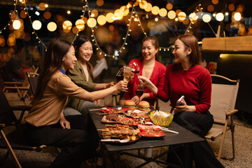 Happy Group of Woman Friends Celebrating Together at Night, Сlinking glasses of dinner at a social gathering.