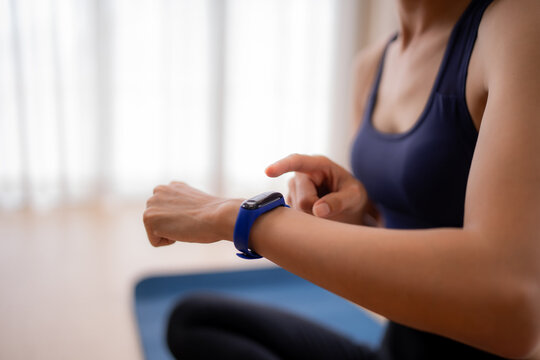 Asian adult female user interact fitness tracker monitoring health activity during home workout for wellness