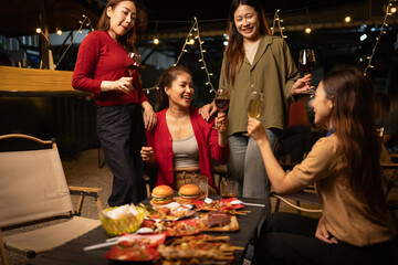 Happy Group of Woman Friends Celebrating Together at Night, Сlinking glasses of dinner at a social gathering.
