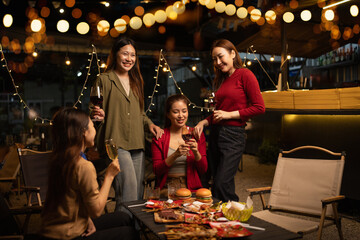 Happy Group of Woman Friends Celebrating Together at Night, Сlinking glasses of dinner at a social gathering.