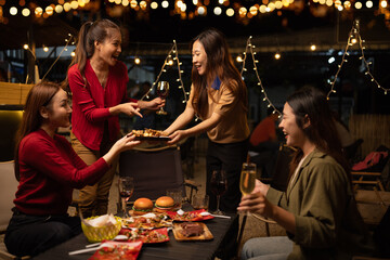 Happy Group of Woman Friends Celebrating Together at Night, Сlinking glasses of dinner at a social gathering.