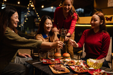Happy Group of Woman Friends Celebrating Together at Night, Сlinking glasses of dinner at a social gathering.