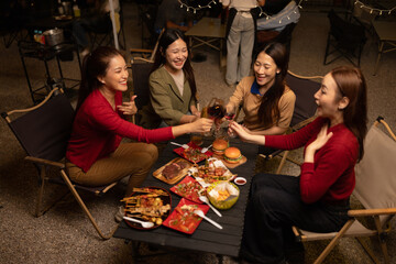 Happy Group of Woman Friends Celebrating Together at Night, Сlinking glasses of dinner at a social gathering.