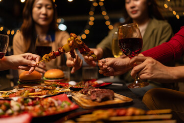 Happy Group of Woman Friends Celebrating Together at Night, Сlinking glasses of dinner at a social gathering.