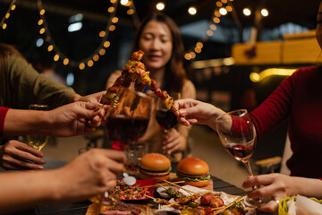 Happy Group of Woman Friends Celebrating Together at Night, Сlinking glasses of dinner at a social gathering.