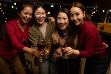 Happy Group of Woman Friends Celebrating Together at Night, Сlinking glasses of dinner at a social gathering.