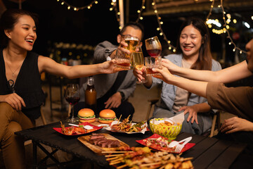 Happy Friends Celebrating Together at Night, Young Asian Group of Friends Having Fun and Toasting Drinks Outdoors At Night, Enjoying a Celebration Concept.