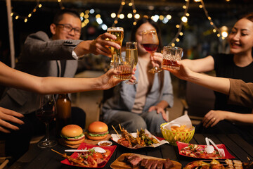 Happy Friends Celebrating Together at Night, Young Asian Group of Friends Having Fun and Toasting Drinks Outdoors At Night, Enjoying a Celebration Concept.