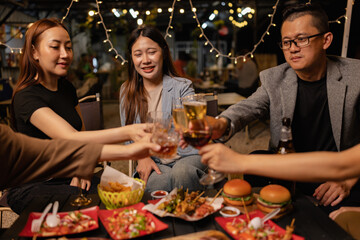 Happy Friends Celebrating Together at Night, Young Asian Group of Friends Having Fun and Toasting Drinks Outdoors At Night, Enjoying a Celebration Concept.