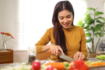 Happy young woman preparing healthy food in the kitchen.