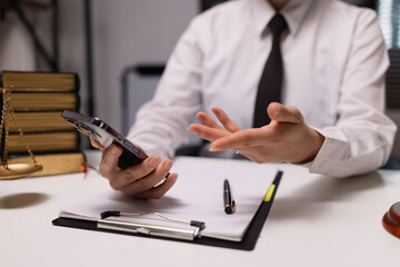 Fototapeta premium Justice and laws concept. Lawyer businesswoman use mobile phone with law book in a modern office.