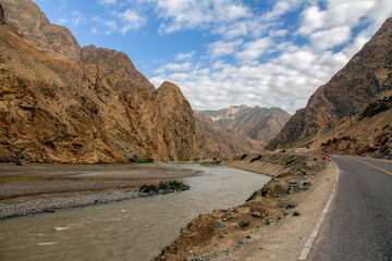 Scenic mountain river road with clear blue sky and white clouds
