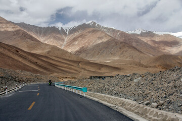 Scenic mountain road with clear sky and snow-capped peaks in the distance