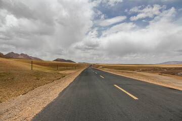 Long straight road extending through vast open landscape under cloudy sky
