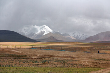 Snow-capped mountains under cloudy sky in vast open land