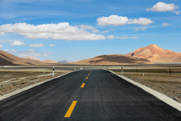 Straight road in vast open landscape under clear blue sky
