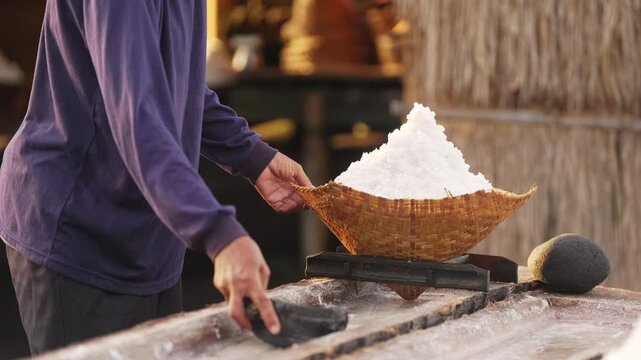 bali traditional sea salt farmer harvesting crystalized coarse salt from coconut trunks, farming