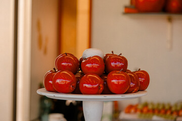 Red candied apples displayed on a white tray, representing a classic festive dessert and traditional sweet treat for holiday markets and celebrations