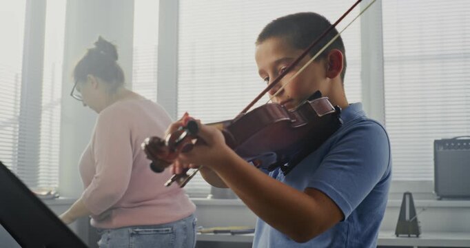 Primary School Boy Practicing Violin in Music Class, Dreaming to Become Musician. Teacher Guiding Artistic Child in Playing Musical Instrument. Musical Education, Violin Training Lesson, Rehearsal.