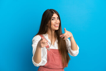 Fototapeta premium Young caucasian woman isolated on blue background surprised and pointing front