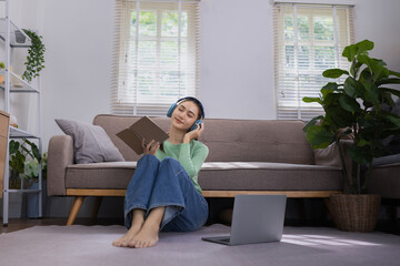 Woman reading a book with blue headphones and a laptop at home, Relaxation & Leisure Learn online Concept.