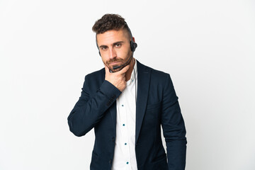 Telemarketer man working with a headset isolated on white background thinking