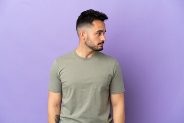 Obraz premium Young caucasian man isolated on purple background looking to the side