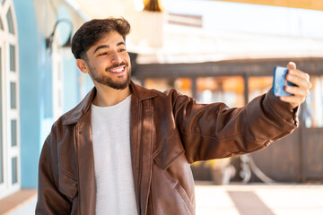 Handsome Arab man at outdoors making a selfie with mobile phone