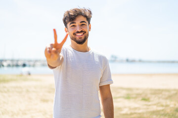 Handsome Arab man at outdoors smiling and showing victory sign
