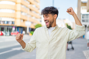 Young Arabian handsome man at outdoors celebrating a victory