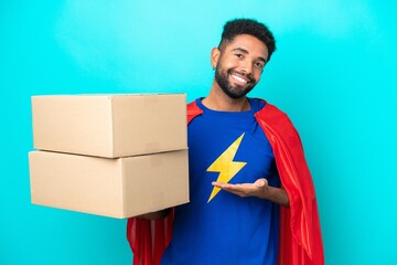 Super Hero delivery Brazilian man isolated on blue background extending hands to the side for inviting to come