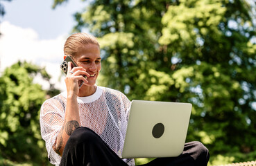 Modern woman working remotely in city park with laptop and smartphone