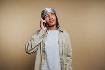 Young man with braided hair wearing a durag, talking on a phone.