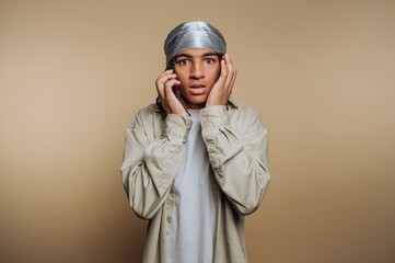 Person wearing a durag and beige shirt, looking surprised.