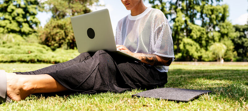 Modern woman working remotely on laptop in green park