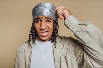 Young man with a confused expression, wearing a durag and casual clothing.