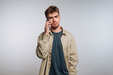 Young man with a serious expression talking on a smartphone.