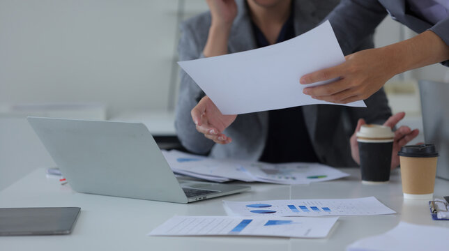 Hand of business team holding a pen, discussing marketing analytics at the office.