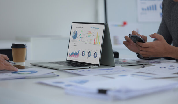 Hand of business team holding a pen, discussing marketing analytics at the office.