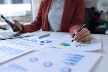 Hand of businesswoman holding a pen, discussing marketing analytics at the office.