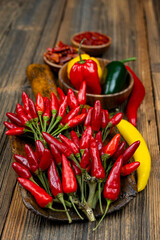 Fresh red chilies and colorful bell peppers on a wooden table