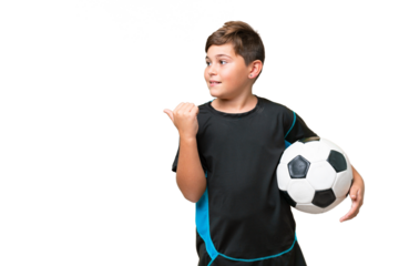 Little caucasian football player kid over isolated chroma key background pointing to the side to present a product