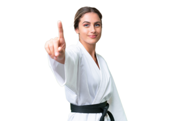 Young Uruguayan woman doing karate over isolated background showing and lifting a finger
