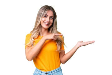 Young Uruguayan woman over isolated background holding copyspace imaginary on the palm to insert an ad