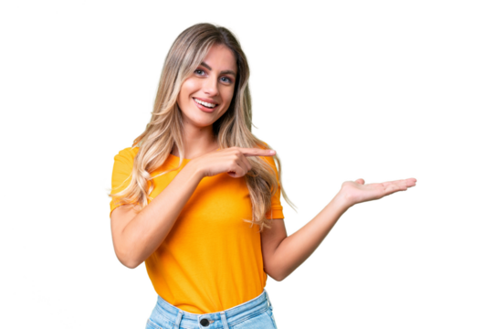 Young Uruguayan woman over isolated background holding copyspace imaginary on the palm to insert an ad