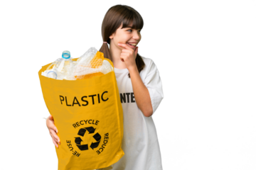 Little caucasian girl holding a bag full of plastic bottles to recycle over isolated background thinking an idea and looking side