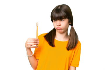 Little caucasian girl brushing teeth over isolated background with sad expression