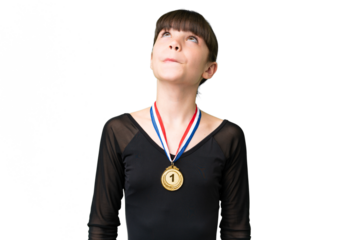 Little caucasian girl with medals over isolated background and looking up