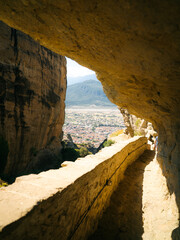 Exterior view of a historic Eastern Orthodox monastery built from stone with traditional Byzantine-style architecture, terracotta roof tiles, wooden stairways and large ceramic pots with plants
